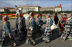 People representing Chinese ethnic minorities walk Sunday in front of the Great Hall of the People at Tiananmen Square in Beijing, where the closed-door session of the Communist Party, held every five years, begins next Monday.