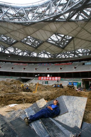 A worker sleeps at the construction site of the "Bird's Nest" stadium, Beijing, China. Construction cost of the stadium overran budget by 50~70 percent. (China Photos/Getty Images)